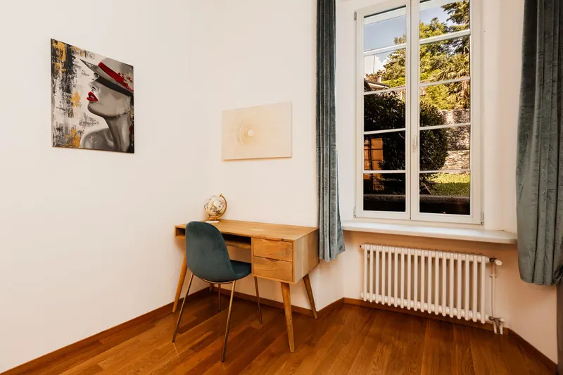 Cozy minimalist interior with a wooden desk by a sunlit window and elegant decor