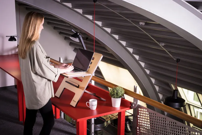 Woman using a laptop on a standing desk indoors in a creative workspace