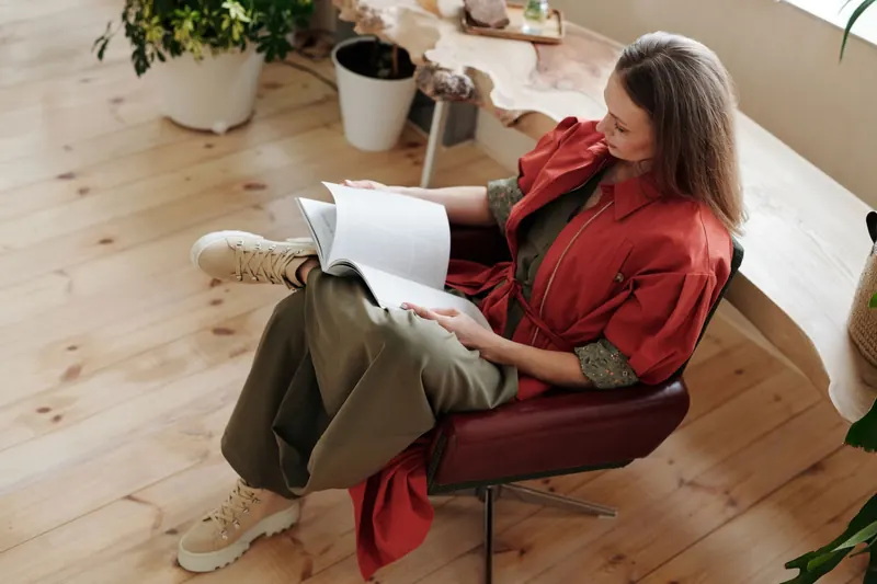 Woman sitting in a stylish chair reading a book. Relaxed and elegant indoor setting