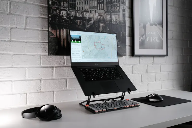 A stylish workspace featuring a laptop, headphones, and a sleek keyboard on a desk